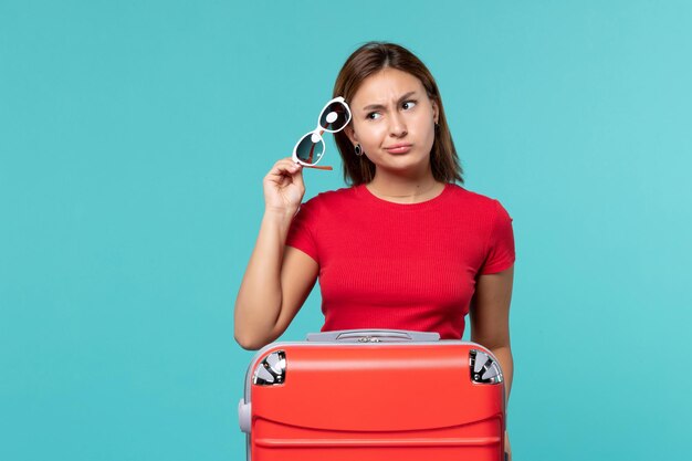 Front view young female with red bag holding her sunglasses on light-blue space