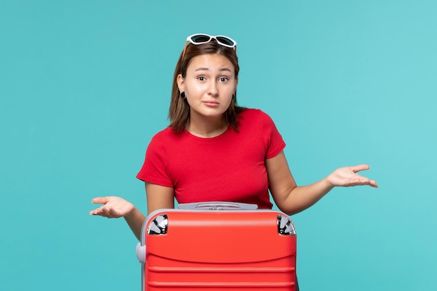 青い床の旅の旅の女性の航海の海で休暇の準備をしている赤いバッグを持つ若い女性の正面図