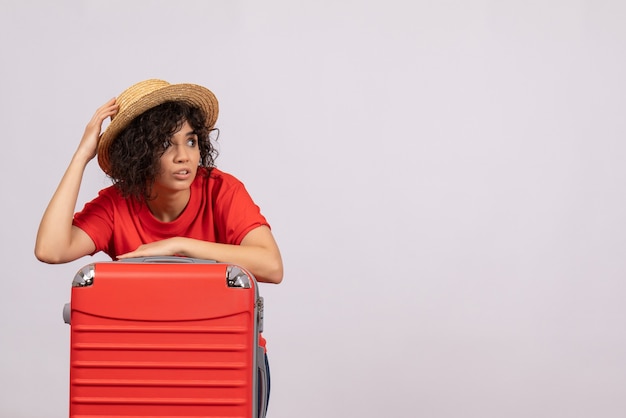 Вид спереди молодая женщина с красной сумкой, готовящаяся к поездке на белом фоне, цвет солнца, путешествие, отдых, туристический рейс, отпуск, самолет