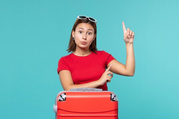 푸른 공간에 휴가를 준비하는 빨간 가방 전면보기 젊은 여성