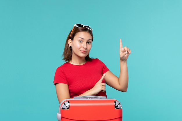 Front view young female with red bag preparing for vacation on blue space