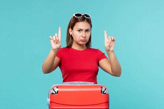 Front view young female with red bag preparing for vacation on blue space