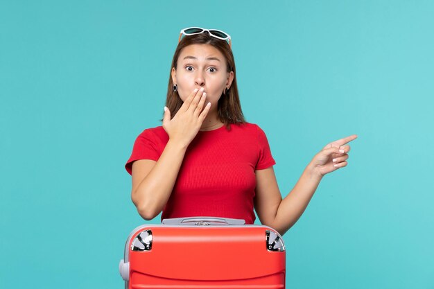 Front view young female with red bag preparing for vacation on blue space