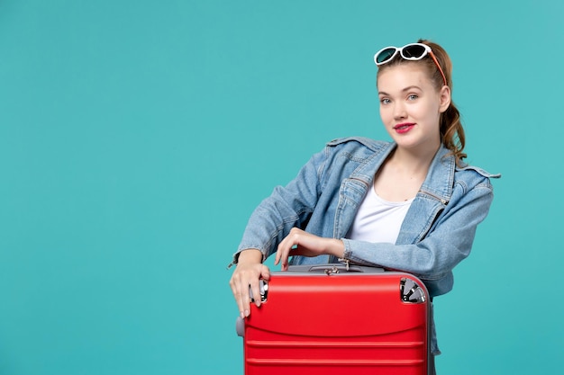 푸른 공간에 휴가를 준비하는 빨간 가방 전면보기 젊은 여성