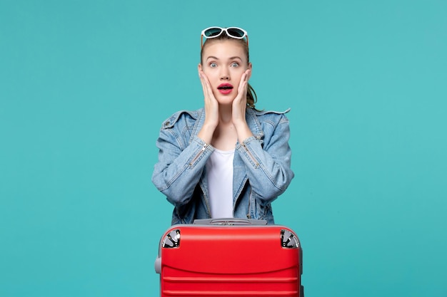 Front view young female with red bag preparing for vacation on a light-blue space