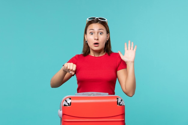 Front view young female with red bag preparing for vacation on a light-blue space