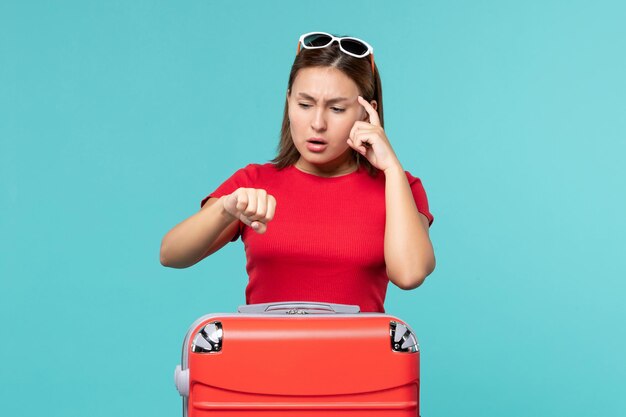 Front view young female with red bag preparing for vacation on a light blue space