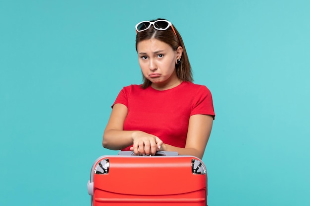 Front view young female with red bag preparing for vacation on light blue space