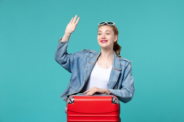 Front view young female with red bag preparing for vacation on light blue space