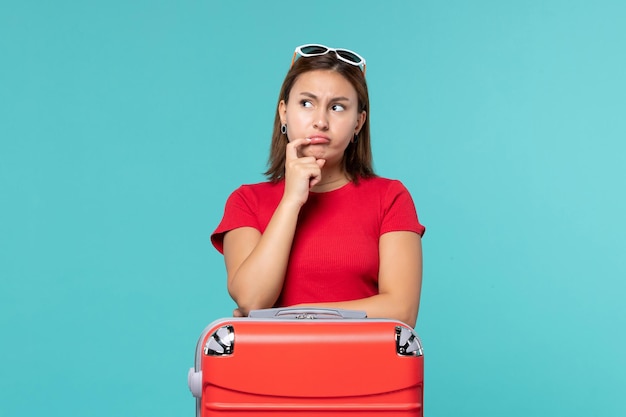 Front view young female with red bag preparing for vacation and thinking on blue space