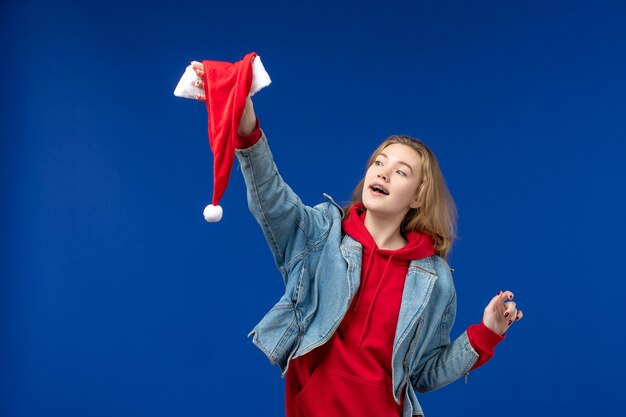 Вид спереди молодая женщина с красной кепкой на синем фоне праздник рождественский цвет новый год