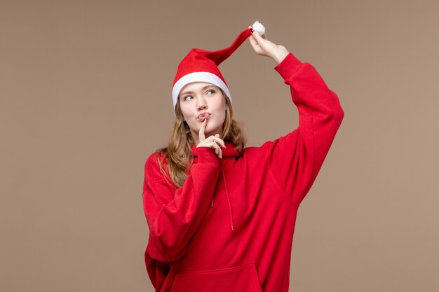 Вид спереди молодая женщина с красной накидкой думает на коричневом фоне рождественские эмоции праздник