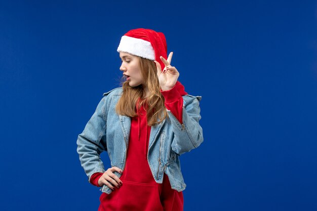 Вид спереди молодая женщина с красной рождественской шапкой на синем пространстве
