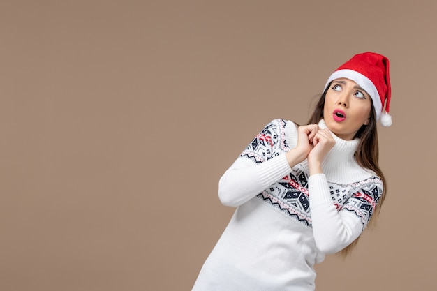 Вид спереди молодая женщина с красной рождественской шапкой на коричневом фоне праздник рождественские эмоции