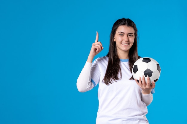 Front view young female with soccer ball on blue wall