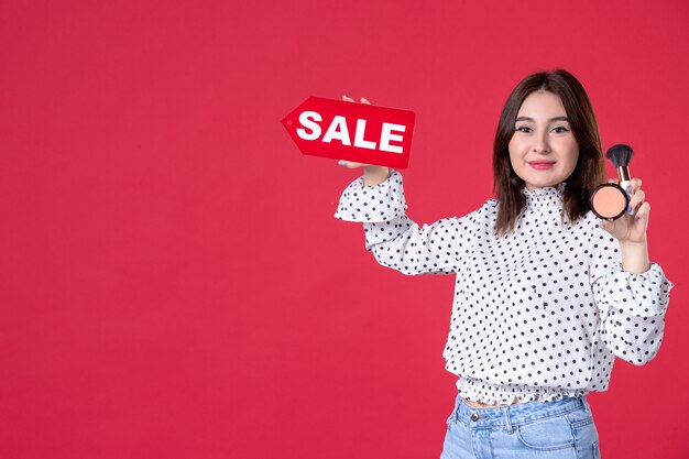 Front view young female with tassel powder for make-up and sale nameplate on red wall