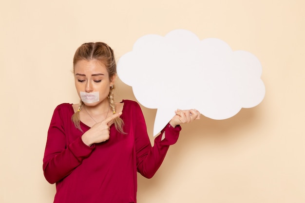 Front view young female with tied mouth holding big white sign on the cream space female photo 