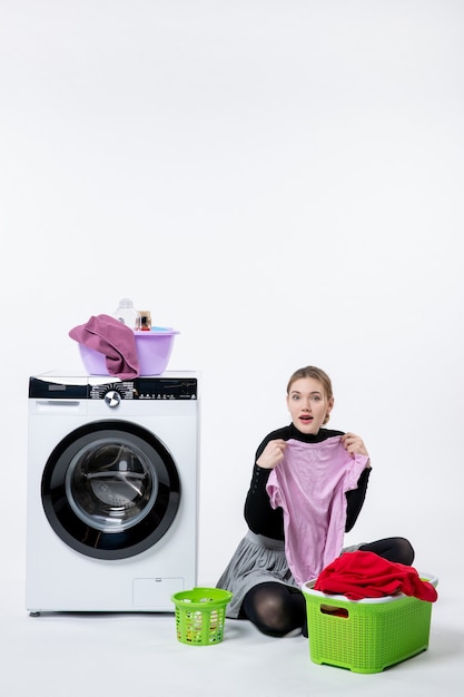 Free photo front view of young female with washing machine folding dirty clothes on the white wall