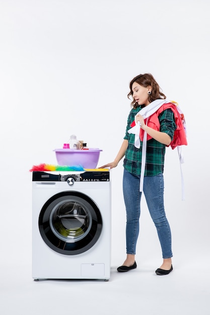 Front view of young female with washing machine on white wall