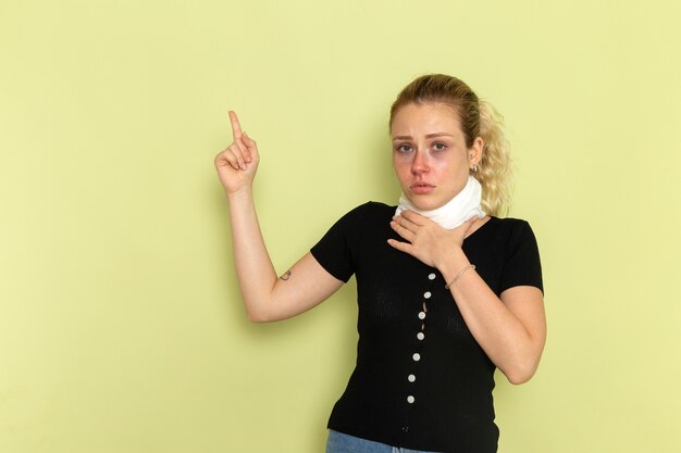 Front view young female with white towel around her throat feeling very ill and sick posing on the light-green desk sickness model medicine health illness