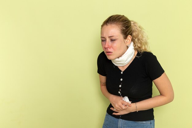 Front view young female with white towel around her throat feeling very sick and ill on light-green desk illness sickness female color health
