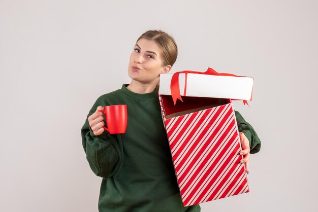 クリスマスプレゼントとお茶のカップを持つ若い女性の正面図