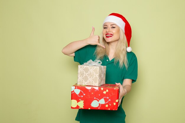 Front view of young female with xmas presents on a green wall