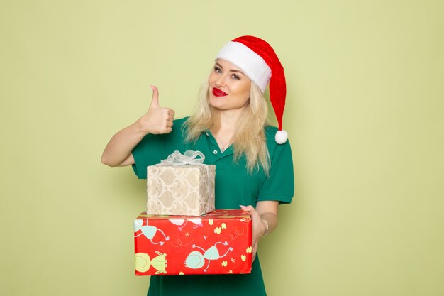 Front view of young female with xmas presents on green wall
