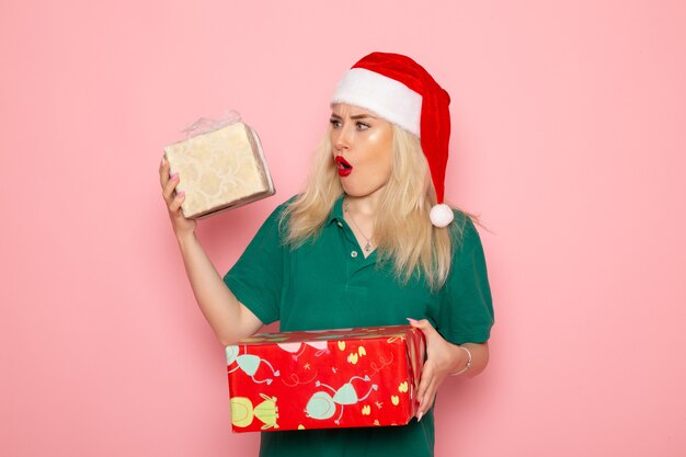 Front view of young female with xmas presents on pink wall