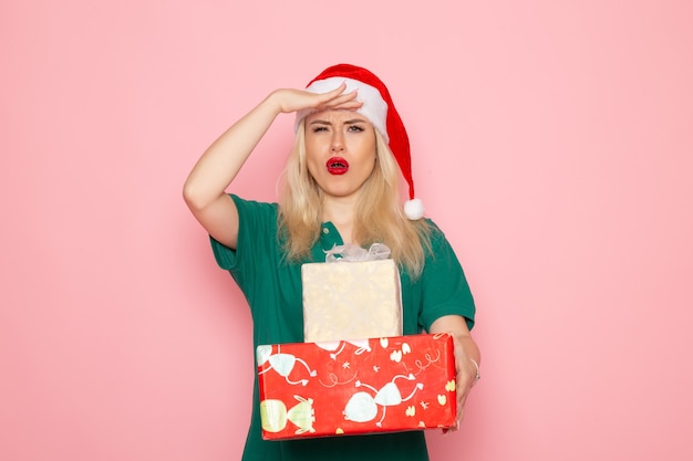 Front view of young female with xmas presents on pink wall