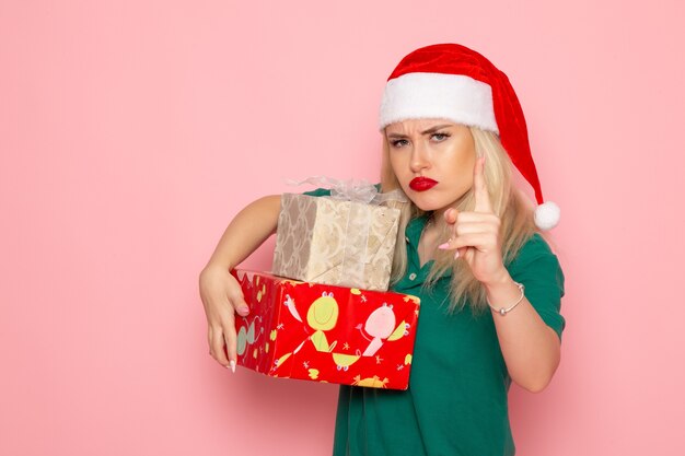 Front view of young female with xmas presents on pink wall