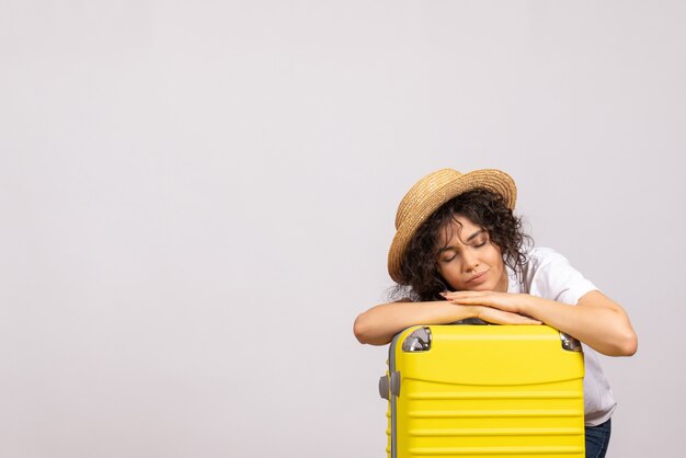 旅行の準備をし、白い背景色の航海休暇飛行機の太陽の残りの観光飛行に疲れを感じている黄色いバッグを持った正面の若い女性