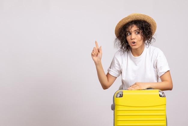 Vista frontale giovane donna con borsa gialla che si prepara per il viaggio su sfondo bianco colore volo resto viaggio aereo vacanza turistica