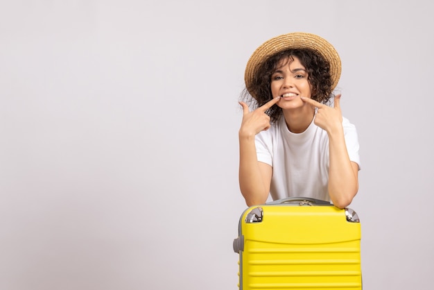 Вид спереди молодая женщина с желтой сумкой, готовящаяся к поездке на белом фоне, цветной полет, рейс, самолет, отдых на солнце, турист
