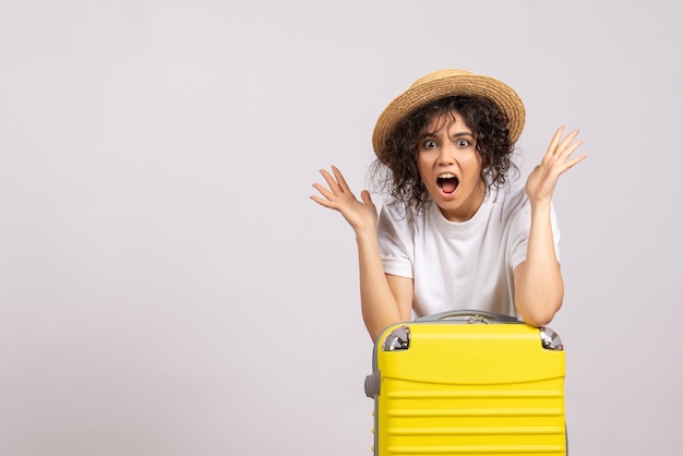 Front view young female with yellow bag preparing for trip on a white background color flight voyage vacation plane sun rest tourist