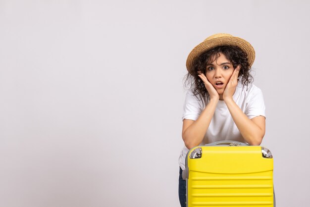 白い背景色の休暇旅行の飛行機の残りの旅行の準備をしている黄色いバッグを持つ正面の若い女性