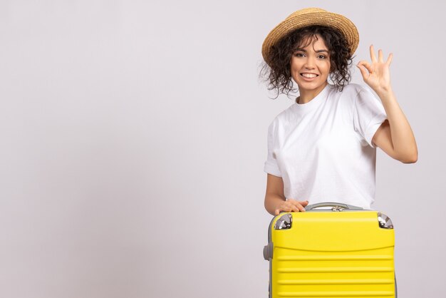 Вид спереди молодая женщина с желтой сумкой, готовящаяся к поездке на белом фоне, цветной отпуск, рейс, рейс, туристический самолет, отдых