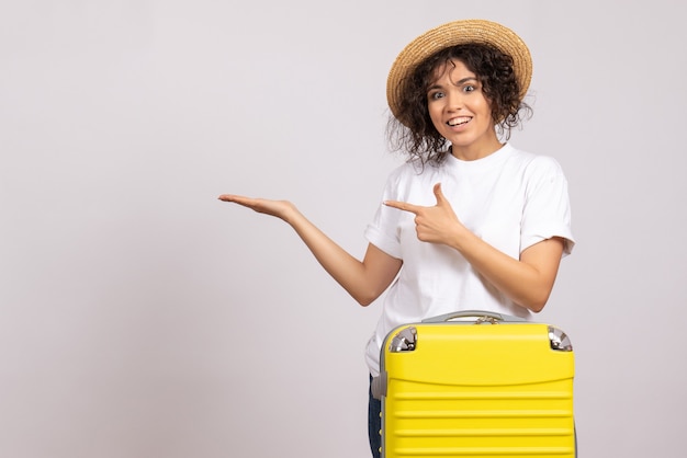 Вид спереди молодая женщина с желтой сумкой, готовящаяся к поездке на белом фоне, полет, отдых, путешествие, туристический отдых, цветное солнце