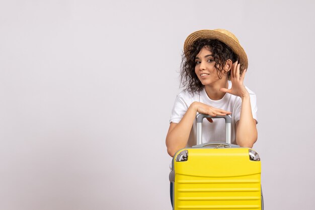 白い背景の太陽の色の旅行飛行機の残りの旅行の旅行の準備をしている黄色いバッグを持つ正面の若い女性