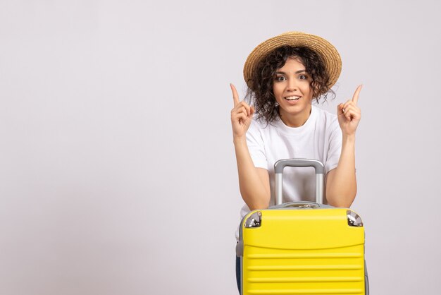 白い背景の太陽の色の旅行飛行機の残りの旅行の旅行の準備をしている黄色いバッグを持つ正面の若い女性