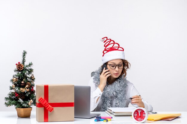 Front view young female at work during holiday days talking on the phone on a white background