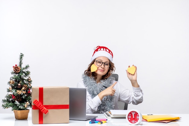 Front view young female worker sitting before her place holding stickers on white background