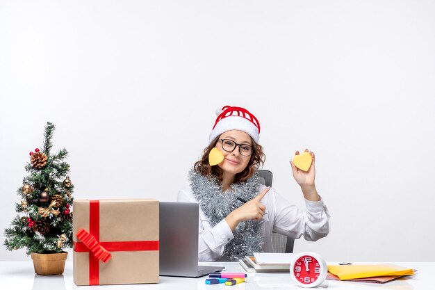 Front view young female worker sitting before her place holding stickers on white background