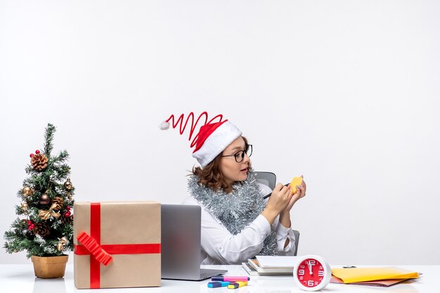 Front view young female worker sitting before her place writing notes on white background