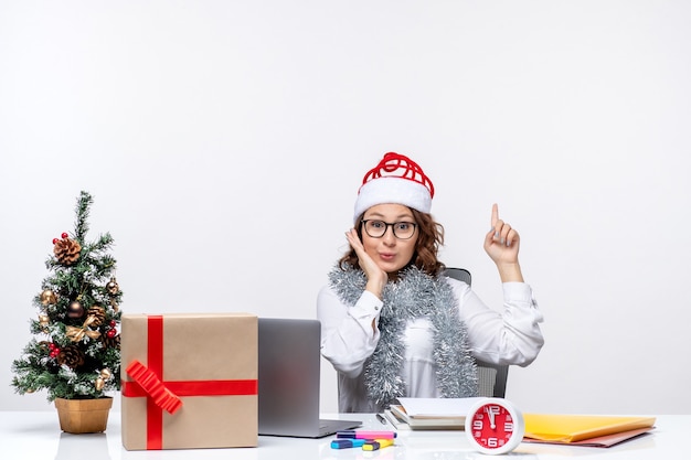 Front view young female worker sitting before her working place excited on white background