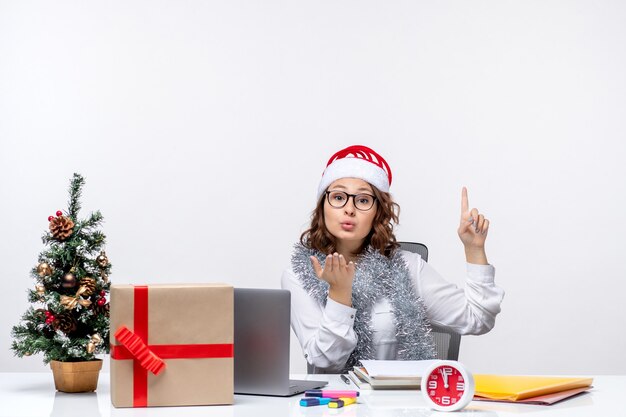 Front view young female worker sitting before her working place sending kisses on a white background