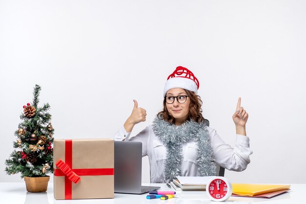 Front view young female worker sitting before her working place on a white background