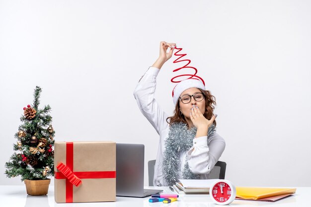 Front view young female worker sitting before her working place on a white background