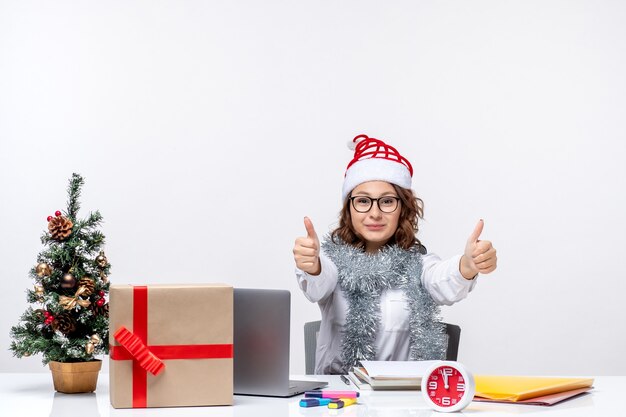 Front view young female worker sitting before her working place on white background