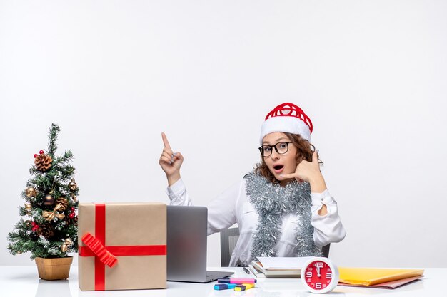 Front view young female worker sitting before her working place on white background